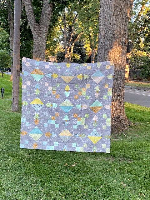 The Highline Quilt Pattern - Julia Wachs Designs - A gray Highline quilt pattern being held outside.