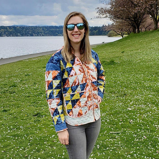 Julia Wachs is photographed on grass in front of a lake with a DIY quilted coat.