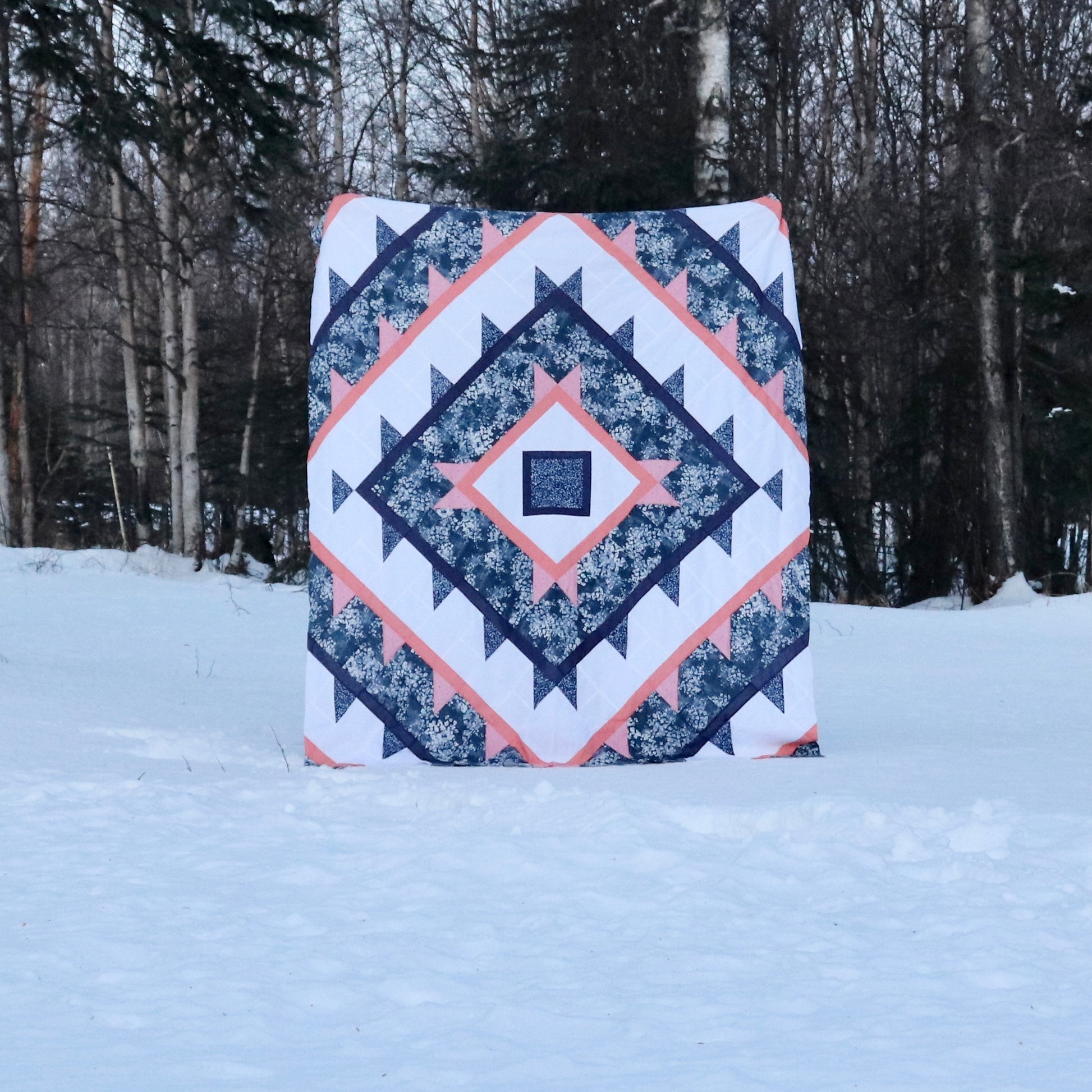 Green Lake Quilt Pattern - Julia Wachs Designs - A Green Lake quilt pattern is held by its maker in the snow.