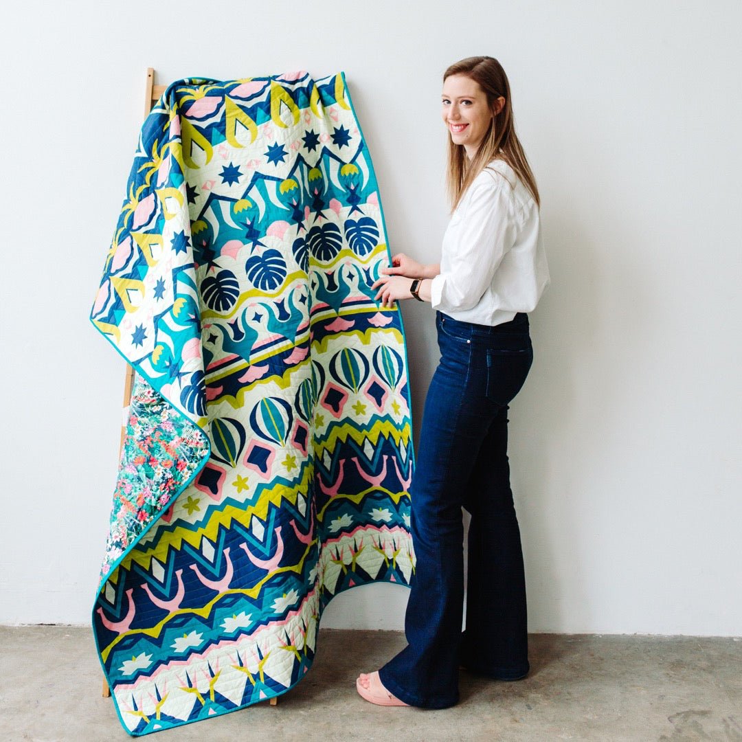 Isla Quilt Pattern - Julia Wachs Designs - Julia standing next to her Isla quilt hanging on a ladder.
