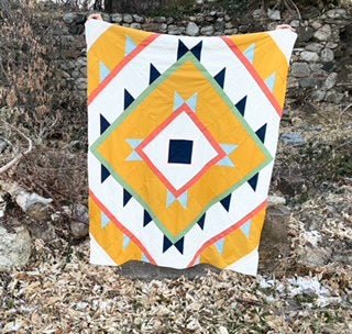 Green Lake Quilt Pattern - Julia Wachs Designs - A yellow Green Lake quilt pattern is held by its maker outside.